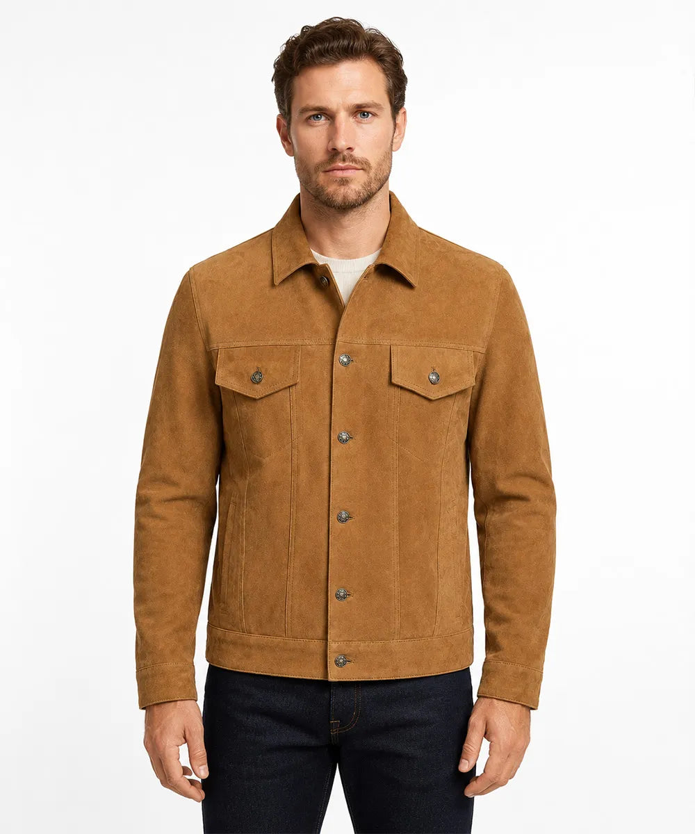 A man wearing a tan suede jacket over a white t-shirt and dark blue jeans, standing against a plain white studio background.