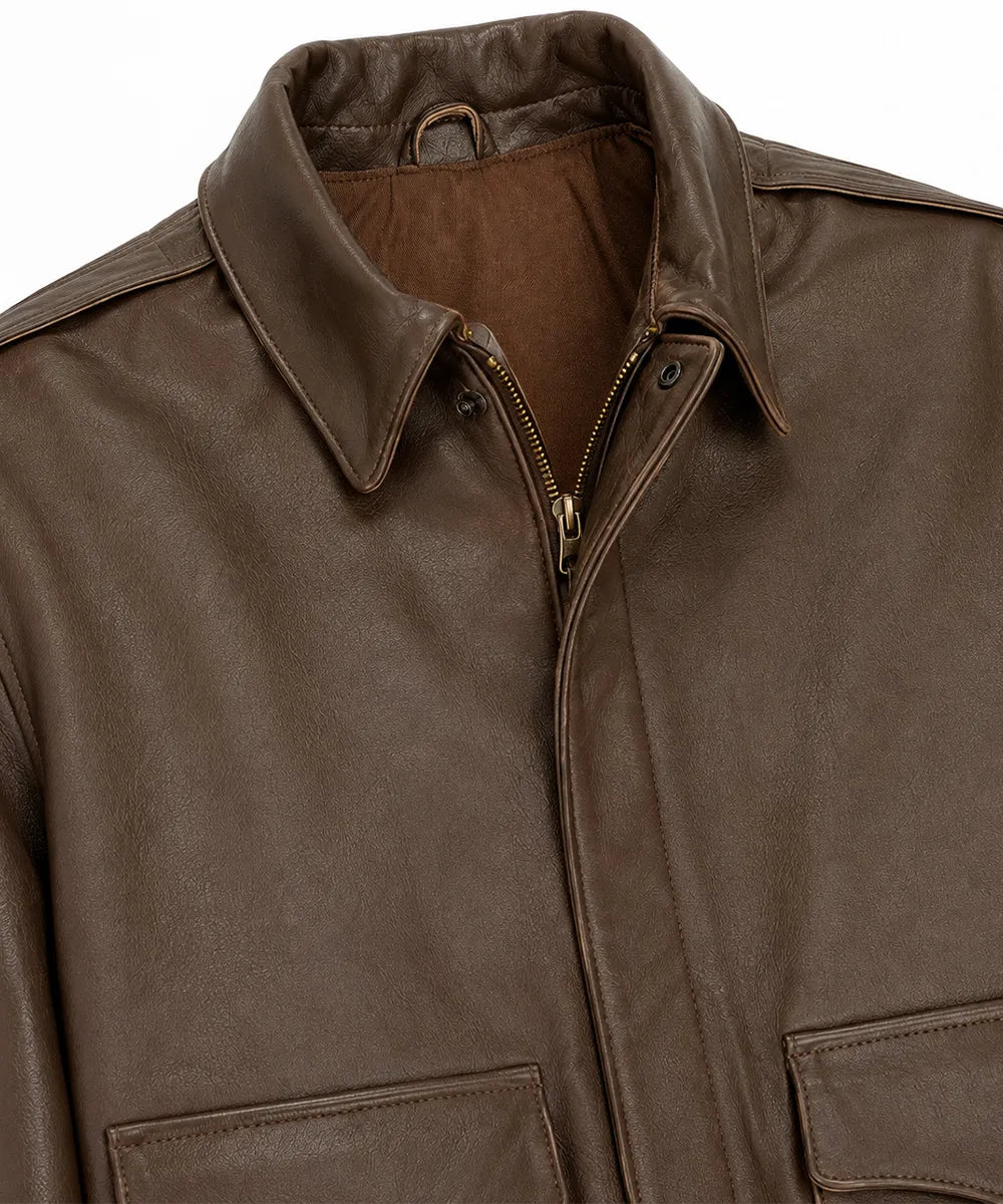 Close-up of a brown leather jacket showing the collar, zipper, and front pockets against a white background.