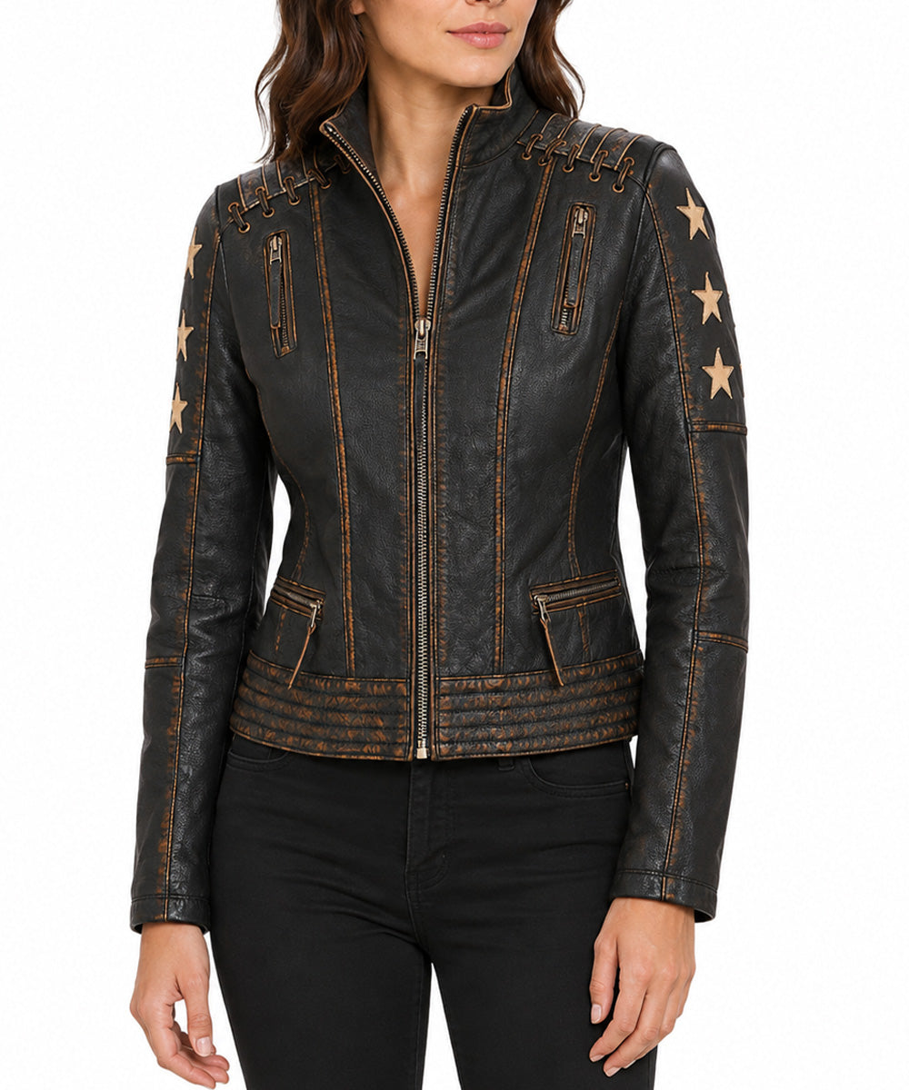 A woman wearing a black distressed leather moto jacket with gold-toned star details on the sleeves and gold contrast stitching, paired with black pants against a white background.