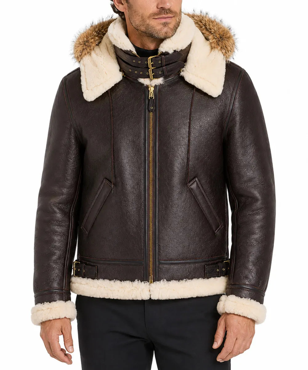 A man wearing a dark brown leather aviator-style jacket with thick cream shearling lining on the hood, collar, cuffs, and hem, paired with black pants against a white studio background.