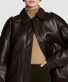 Brown leather bomber jacket made with brown sheepskin worn by a model on a plain background