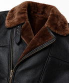 Close-up of brown fur collar, throat strap and brass cross-zip on black sheepskin jacket