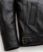 Detail of banded leather cuff, welt hand pocket and brass buckle side adjuster