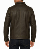 A man viewed from the back wearing a dark brown leather jacket and dark blue jeans against a plain white background.