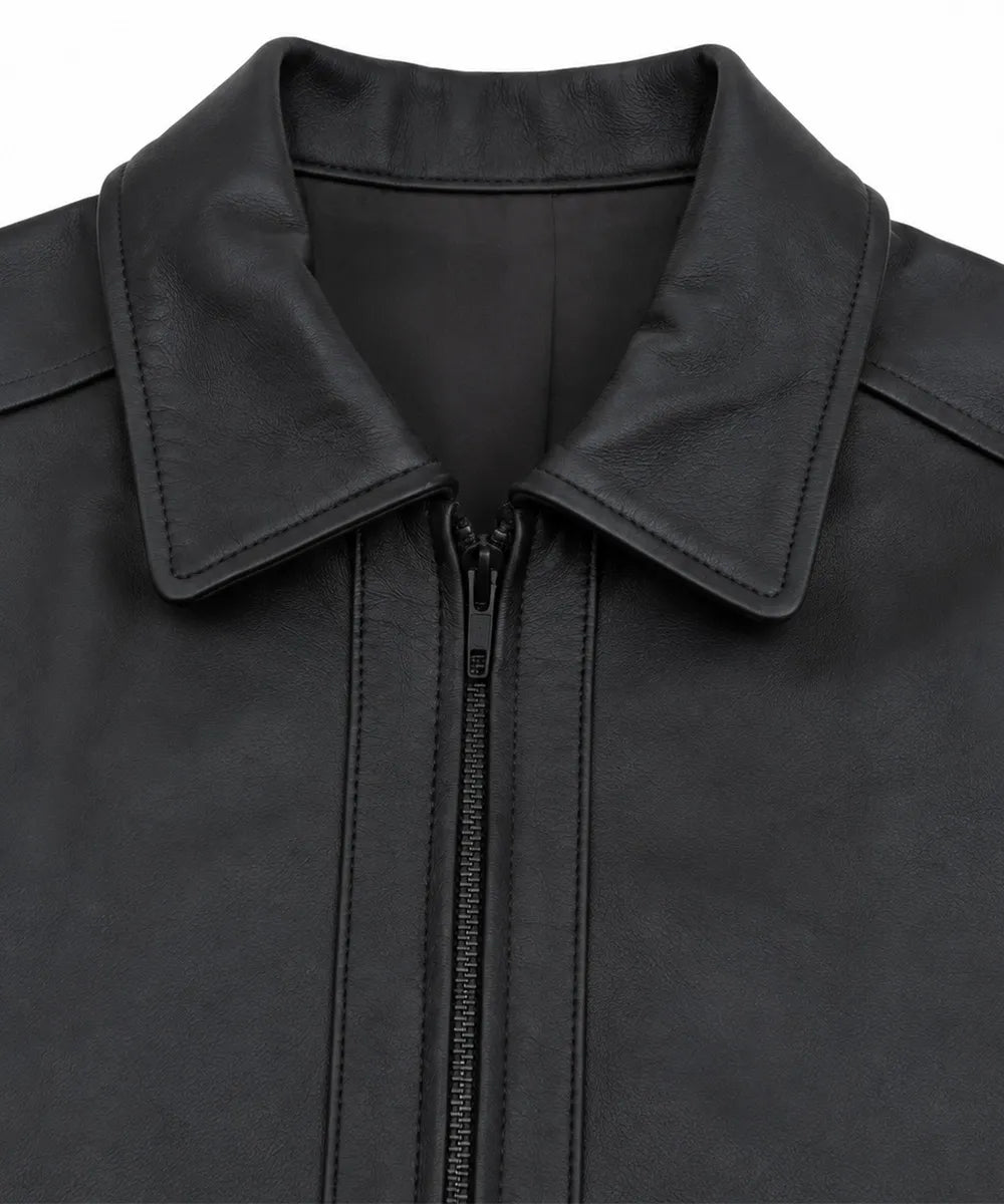 Close-up of a black leather jacket with a wide collar and a front zipper, shown against a plain white background.