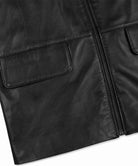 Close-up of a black leather jacket showing a front zip closure and a flap pocket on a white background.