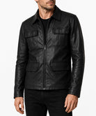 A man wearing a black leather jacket with a front zipper, collar, and four flap pockets, photographed against a plain light background.