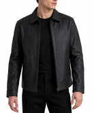A man wearing a black leather jacket over a black t-shirt and black pants, shown from the neck down against a plain white background.