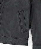 Close-up of a black faux-leather jacket showing a vertical welt pocket and zipper detail against a white background.