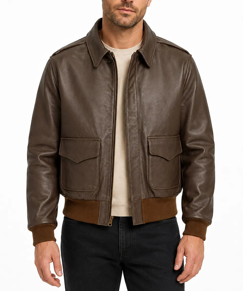 A man wearing a brown leather bomber jacket with a tan crewneck sweater and black jeans, photographed against a plain white background.