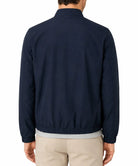 A man viewed from the back wearing a dark navy blue lightweight jacket with a high collar and elasticated hem, paired with beige pants and a light gray undershirt, against a plain white background.