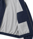 Close-up of a colorblock windbreaker jacket showing a heather gray body, navy blue sleeve and side panel, and silver zippers.