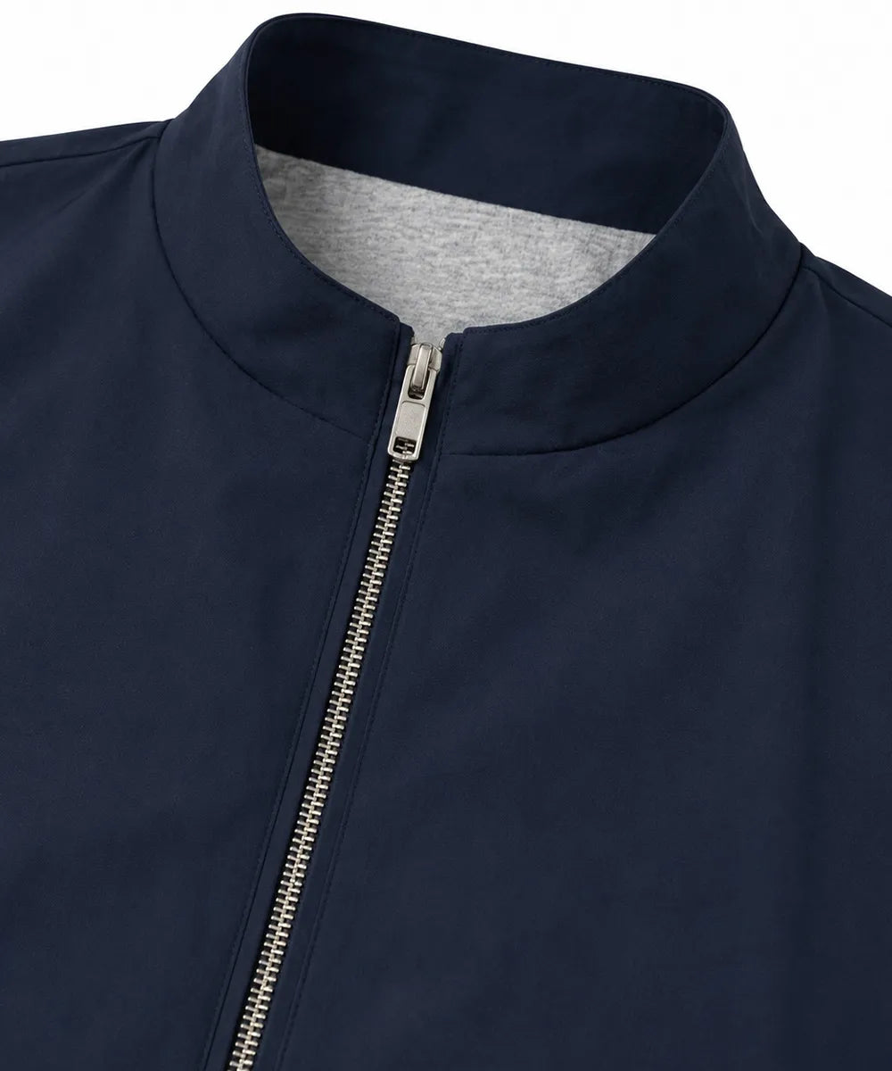 Close-up of a navy blue jacket with a stand-up collar, a silver metal zipper, and a heather gray inner lining visible at the collar.