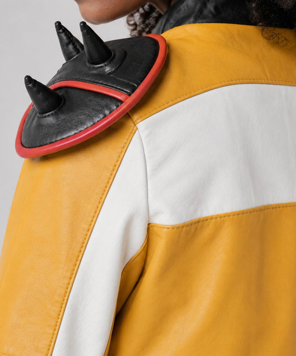 Close-up of the Rumi Kpop Demon Hunters Jacket showing embroidered graphic patches, premium stitching, and yellow leather finish.