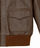 Close-up of a brown leather jacket showing a flap pocket and a ribbed brown knit hem against a white background.