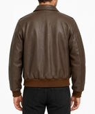 A man viewed from the back wearing a dark brown leather jacket with ribbed knit trim at the hem and cuffs, paired with black jeans, against a plain white background.